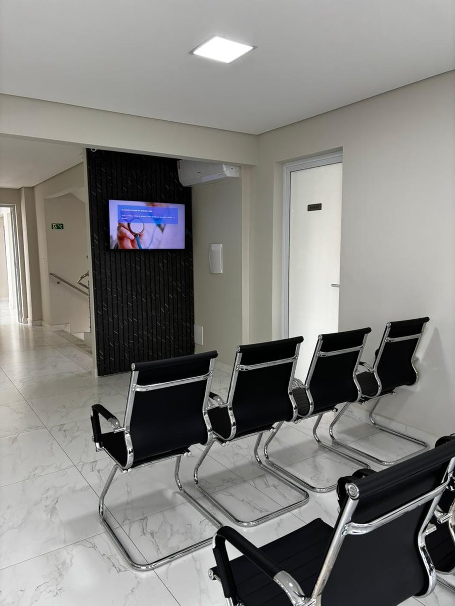 Sala de espera com piso de mármore claro e cadeiras pretas